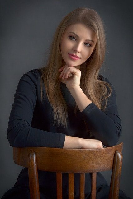 a woman sitting on a chair, pretending it's her partner's face